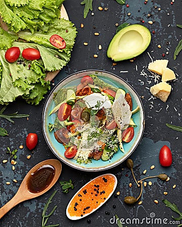 Exotic mixed salad of fish ribbons, avocado slices and red caviar, lettuce, greens and tomatoes garnished with Stock Photo