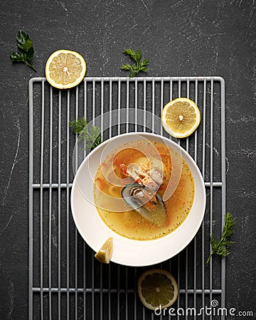 Exotic noodle and mussel soup and lemon slices. Top view of white bowl on black background. Spicy oriental dish Stock Photo