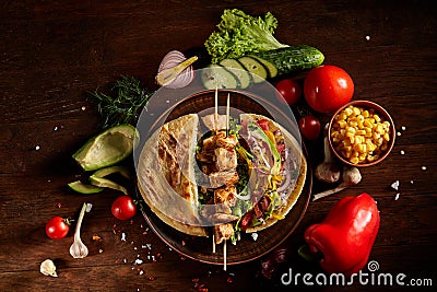 Exotic still slife with pita, fresh vegetables and kebab over wooden background, selective focus. Stock Photo