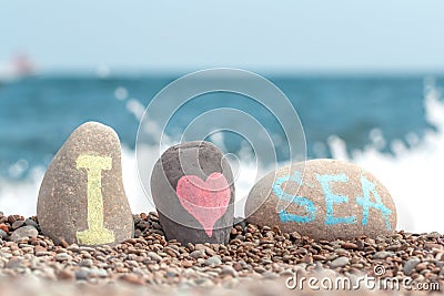 Tropical beach and stones with handwritten I love sea. Blue sea and wave splash with foam. Pebble beach Chesil for summer holiday Stock Photo