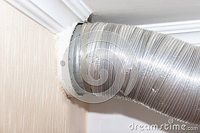 Expandable metallic aluminium corrugated air-conditioning ventilation pipe in kitchen connecting a cooker hood and a ventilation Stock Photo