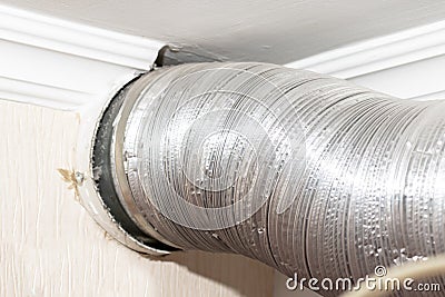Expandable metallic aluminium corrugated air-conditioning ventilation pipe in kitchen connecting a cooker hood and a ventilation Stock Photo