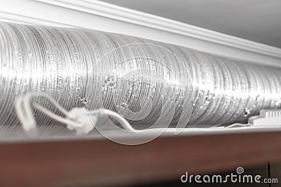 Expandable metallic aluminium corrugated air-conditioning ventilation pipe in kitchen connecting a cooker hood and a ventilation Stock Photo