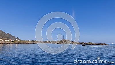 Expansive seascape capturing vibrant red Rorbu on Moskenes' jagged coastlines and a tourist-filled speedboat Stock Photo