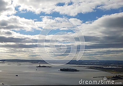 Sweeping aerial view of New York Harbor with Statue of Liberty and Ellis Island in the distance, with cloudscape Stock Photo