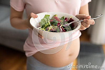 Expectant mother holding bowl with fresh vegetable salad Stock Photo