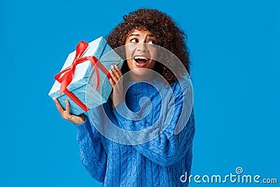 Expectations, holidays and winter concept. Excited cheerful african-american woman shaking box with gift, want unwrap Stock Photo