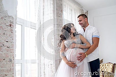 In expecting. Happy pregnant pair in fashion clothes posing in studio Stock Photo