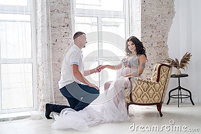In expecting. Happy pregnant pair in fashion clothes posing in studio Stock Photo