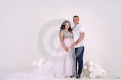 In expecting. Happy pregnant pair in fashion clothes posing in studio Stock Photo