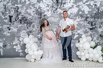 In expecting. Happy pregnant pair in fashion clothes posing in studio Stock Photo