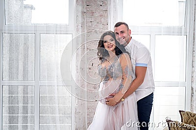 In expecting. Happy pregnant pair in fashion clothes posing in studio Stock Photo