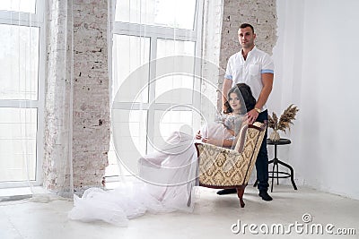 In expecting. Happy pregnant pair in fashion clothes posing in studio Stock Photo