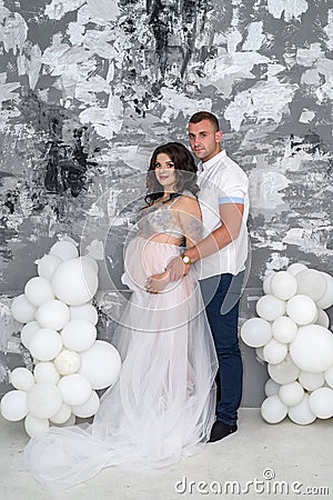 In expecting. Happy pregnant pair in fashion clothes posing in studio Stock Photo