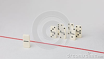 Expelled from the group, unable to cross the red line that separates them. Scene with group of domino. Concept of Stock Photo