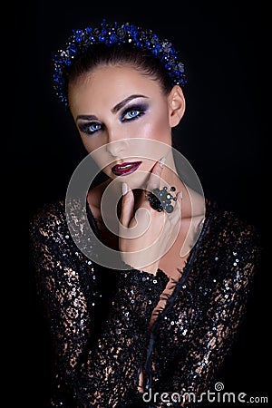 Expensive jewelry wreath earrings and ring on a beautiful elegant brunette girl with a bright evening make-up in a black even Stock Photo
