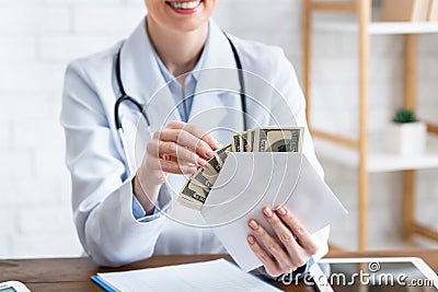 Expensive medicine. Smiling doctor counts money in envelope Stock Photo