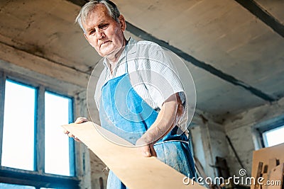 Experienced carpenter checking if plank is plane Stock Photo