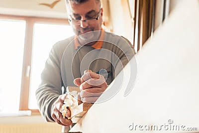 Experienced carpenter planing wood in workshop Stock Photo