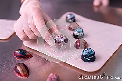 Experienced chocolatier holding sweet with silver coating Stock Photo