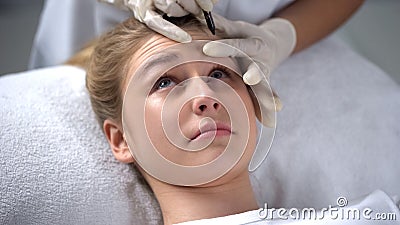 Experienced cosmetologist marking position of wrinkles on girls forehead Stock Photo