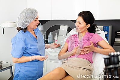 Experienced cosmetology doctor tells a young female patient about the health of the female breast Stock Photo