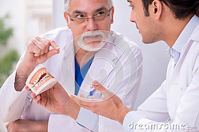 Experienced doctor dentist teaching young male assistant Stock Photo