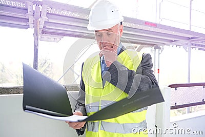 Experienced elderly construction worker, construction crew chief, construction engineer in white helmet protection inspecting at Stock Photo