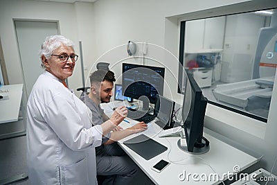 Experienced female doctor and her junior colleague reviewing CT scan results Stock Photo