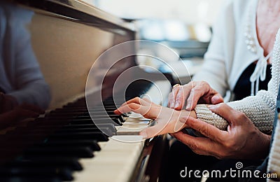 Experienced hand of old music teacher helps child pupil Stock Photo