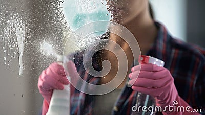 Experienced housewife spraying lot of washing-up liquid on window to clean it Stock Photo