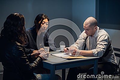 An experienced investigator and a female police officer interrogate the suspect Stock Photo