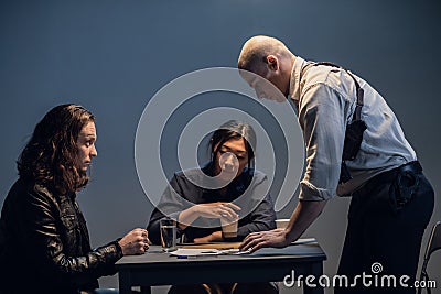 An experienced investigator and his assistant are interrogating the suspect at the police station Stock Photo