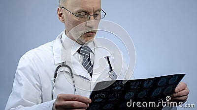 Experienced male therapist looking at patients brain scan, checking MRI results Stock Photo