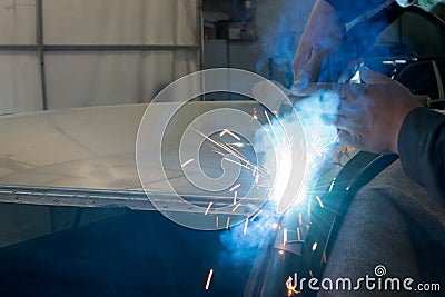 Experienced man performs work on body repair car with a welding machine. Stock Photo