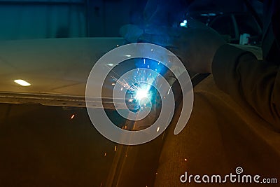 Experienced man performs work on body repair car with a welding machine. Stock Photo