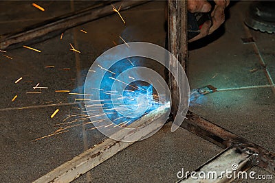 An experienced man performs work with a welding machine by fastening metal parts in an industrial workshop Stock Photo