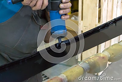 An experienced man in working clothes applies a black sealant Editorial Stock Photo