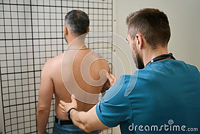 Qualified physiotherapist performing spinal palpation in adult man Stock Photo