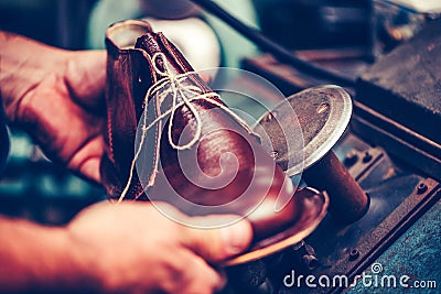 Experienced shoemaker using special machine tool for making a shoes Stock Photo