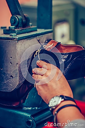 Experienced shoemaker using special machine tool for making a shoes Stock Photo