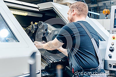 Experienced worker changing tool setup of lathe machine Stock Photo