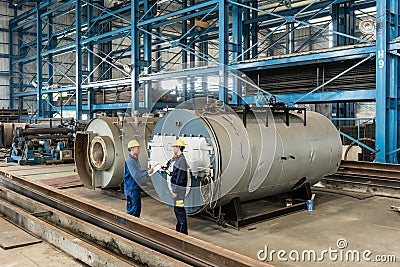 Experienced worker checking the quality of manufactured boilers Stock Photo