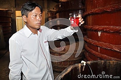 An expert is checking the quality of the fish sauce sample which is a traditional sauce in Vietnam, from a fermented tank in Phu Editorial Stock Photo