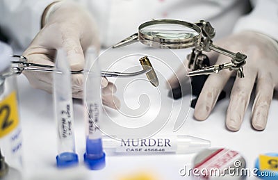 Expert police examines a bullet cap in scientific laboratory with magnifying glass Stock Photo