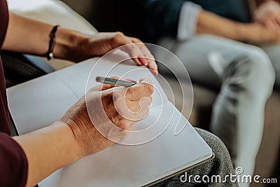 Focused experienced doctor of psychology writing down notes about problems Stock Photo