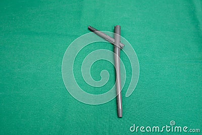 Explanted femoral nail lies on a green surgical drape Stock Photo