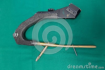 explanted femoral nail with locking screw lies on a green surgical drape Stock Photo