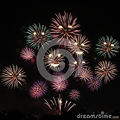 Exploding fireworks illuminate the night sky in a dazzling array of colors, including Stock Photo