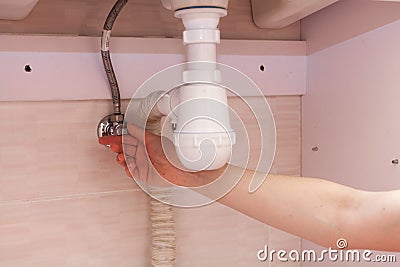 Exposed plastic plumbing attached to a copper joint with a shut-off valve under a white sink. Shut off the water supply to the sin Stock Photo